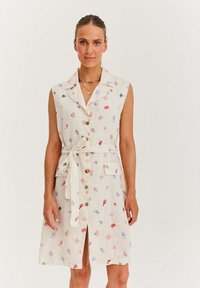 Sukienka lniana bez rękawów w kolorze ecru z kwiatowym wzorem, z kołnierzykiem, zapięciem na guziki, paskiem w talii i dwiema kieszeniami.