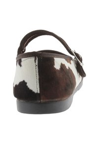 Zapato slip-on con patrón de piel de vaca en una combinación de colores marrón y blanco, con un respaldo redondeado, correa elástica y suela de goma negra.