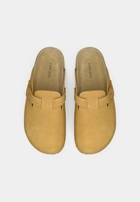 Ταμπά σουέντ τσόγκες με απαλό υφή, φαρδιές ανοίγματα και διακοσμητικό λουράκι στην κορυφή. Ίσιες σόλες, μινιμαλιστικός σχεδιασμός.