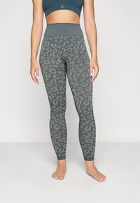 Høyt liv leggings i mørk teal med et grått leopardmønster, med en sømløs design og elastisk, teksturert stoff.