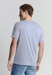 Lichtblauwe katoenen T-shirt met korte mouwen en een ronde halslijn. Gladde textuur, casual ontwerp en een iets relaxte pasvorm.