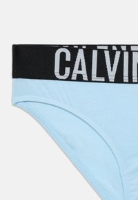 Világoskék pamut alsónadrág fekete rugalmas derékkal, ami „CALVIN” felirattal van ellátva szürke betűkkel. Sima textúra és klasszikus szabású dizájn.