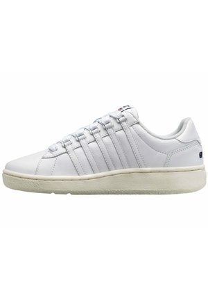 Sneaker in pelle bianca con design a basse, suola in gomma testurizzata e sei paia di fori per i lacci. Un branding minimalista è visibile sulla linguetta.