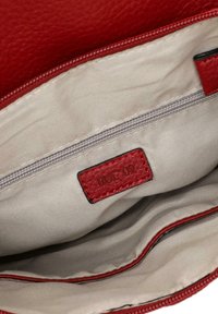 Intérieur d'un sac à main en cuir rouge, avec une doublure beige, une poche zippée et une petite étiquette marquée "RUE 09". Texture lisse avec des coutures soignées.