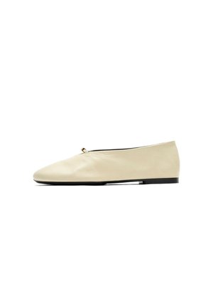 Ballerine en cuir couleur crème avec un petit nœud, bout arrondi et semelle noire, représentée de profil sur fond blanc.