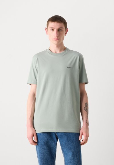 T-shirt vert clair avec un col rond et des manches courtes, présentant un petit logo noir "BOSS" sur la poitrine. Tissu doux et lisse.