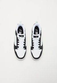 Chaussures de sport noir et blanc avec des accents vert menthe, tige en synthétique, orteil perforé et lacets plats. Logo de sport visible sur le côté.