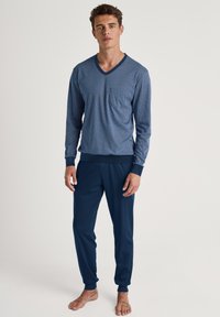 Heren loungewear set met een lange mouwen blauwe top met geometrische patronen en marineblauwe onderkant met ribgebreide boorden, gemaakt van zacht materiaal.