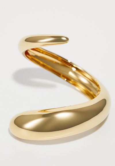 Gold-tone metal cuff bracelet with a smooth, curved design. Features a sleek, shiny surface and a gentle taper towards the ends.