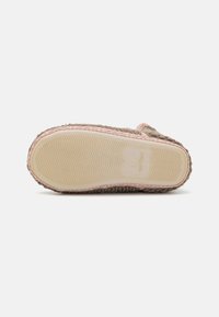 Footwear sole featuring a textured beige rubber base with pink stitching. The upper has a woven fabric look with braided edges.