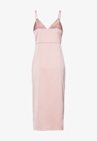 Robe midi en satin rose clair avec fines bretelles spaghetti et décolleté en V sur fond blanc.