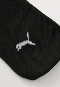 Calzino nero in tessuto a coste, con il logo PUMA ricamato in grigio a forma di gatto che salta.