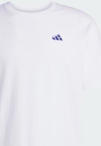 T-shirt bianca in cotone con scollatura a girocollo. Presenta un piccolo logo ricamato viola sulla parte sinistra del petto. Maniche corte.