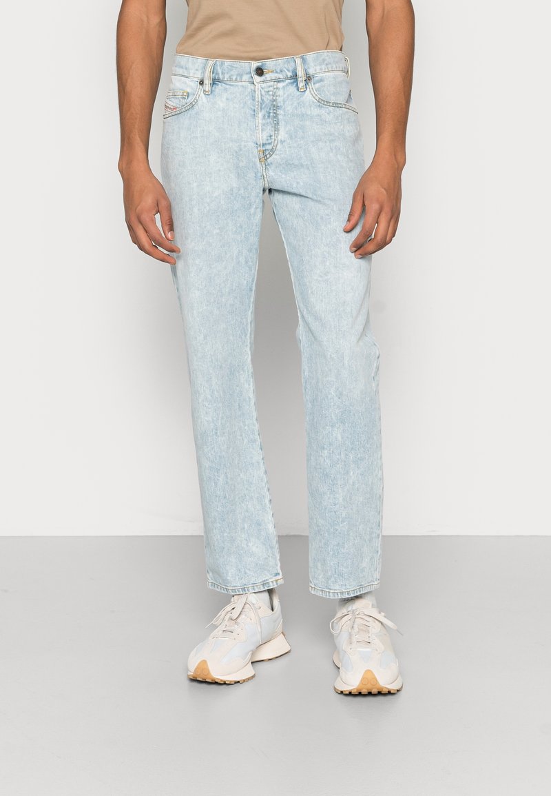 Light blue denim jeans with a faded wash, straight leg cut, and front pockets. Paired with light grey sneakers.