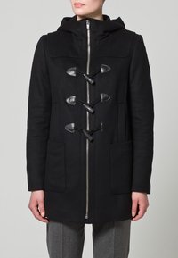 Cappotto con cappuccio nero caratterizzato da chiusure in pelle a bottone, zip frontale e due tasche laterali. Il tessuto ha una consistenza liscia con un taglio dritto.