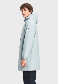 Parka impermeabile azzurro chiaro con cappuccio, polsini elasticizzati e zip a tutta lunghezza. Presenta il logo sull'avambraccio e una vestibilità ampia.