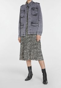 Szara kurtka dżinsowa z czterema kieszeniami z przodu, zapięcie na guziki i kołnierz mandarynka. Noszona na czarno-białą sukienkę w wzory oraz czarne botki na obcasie.