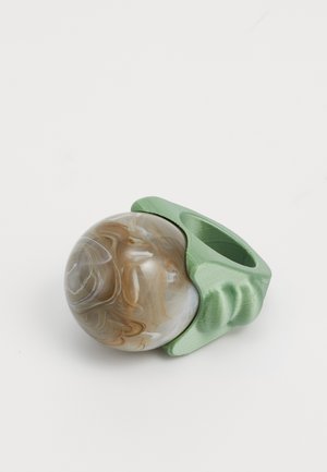 Spheroidi marbrim ruske zatvoreno u teksturiranoj zelenoj držaču, sa jedinstvenim zakrivljenim dizajnom i izrezom za prst.