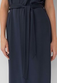 Dunkelblaues Kleid aus glattem Material, mit einem gebundenen Gürtel in der Taille und dezenten Nahtdetails. Figurbetonte Silhouette mit einem schlanken Design.