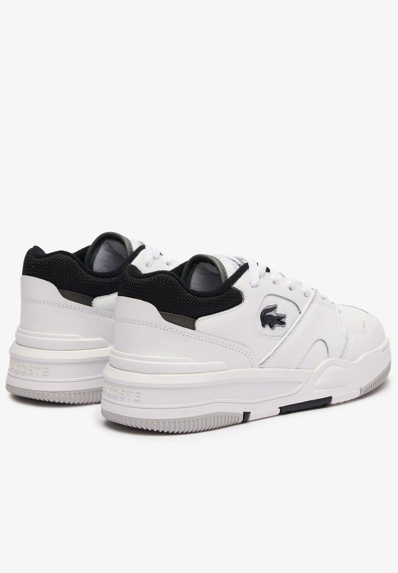 Baskets de sport blanches avec un dessus en cuir texturé, un col rembourré et un accent en maille noire au niveau du talon. Détail du logo sur le côté.