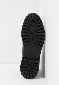 Semelle de bottes noires avec des crampons profonds en forme d'étoile, taille 40, embossée avec le logo Tommy Hilfiger.
