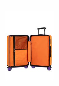 Pomarańczowa walizka z twardą skorupą, podwójnymi przegrodami, siatkową kieszenią, zamkami błyskawicznymi oraz wysuwanym uchwytem. Posiada fioletowe kółka ułatwiające przemieszczanie.