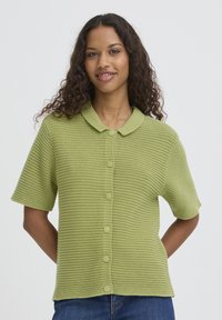 Cardigan tricoté vert à manches courtes avec un motif texturé, fermeture à boutons et col à revers. Coupe décontractée, idéal pour superposer.