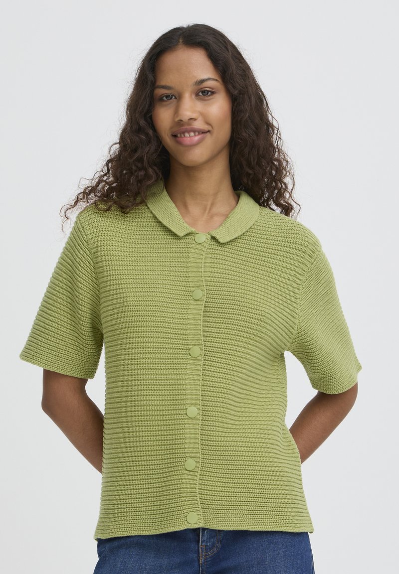 Cardigan tricoté vert à manches courtes avec un motif texturé, fermeture à boutons et col à revers. Coupe décontractée, idéal pour superposer.