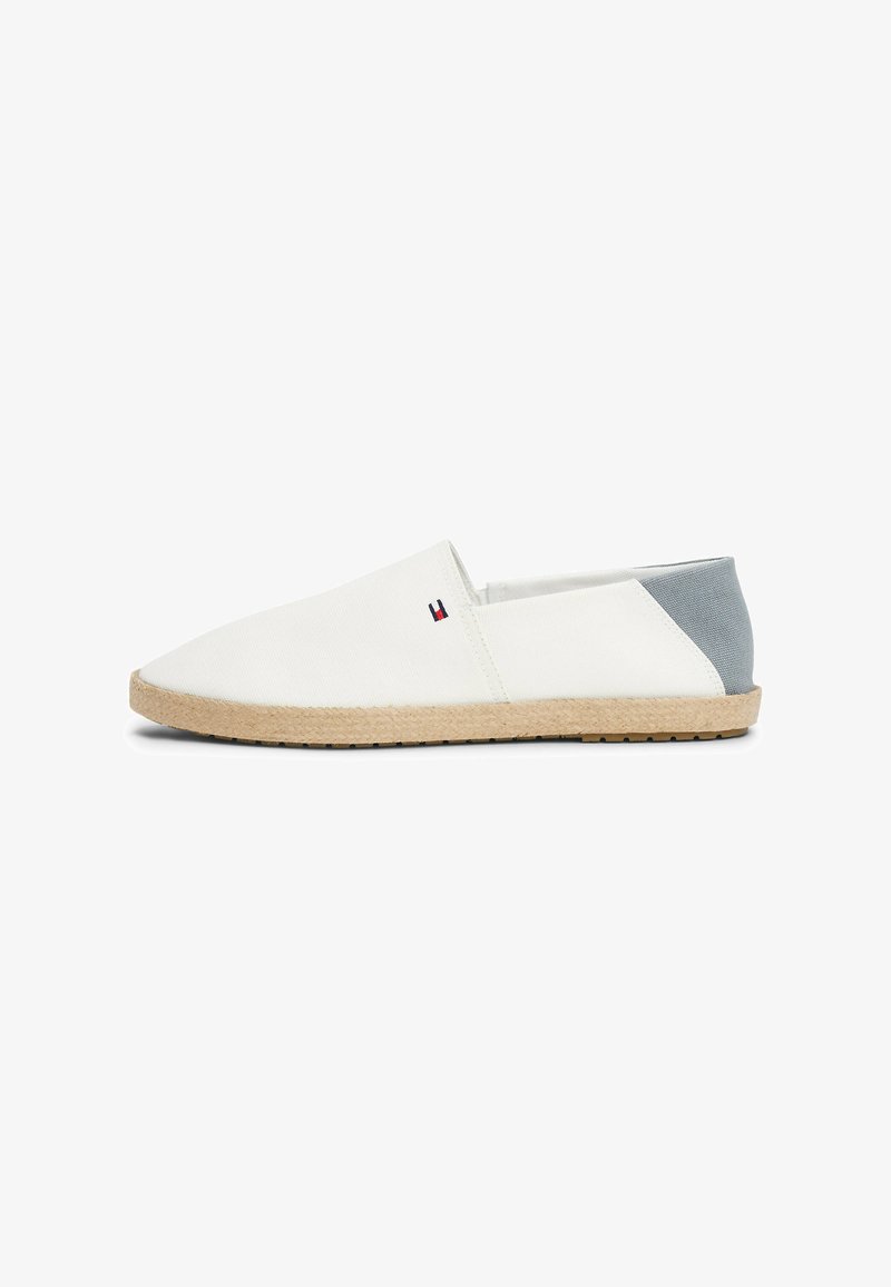 Canvas slip-on sko i hvid med en grå hæl. Naturlig jute sål med tekstureret overflade. Lille logo accent på siden. Rund tå design.