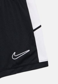 Μαύρο αθλητικό σορτς με λευκές διχτυωτές λεπτομέρειες, με μαύρο και λευκό λογότυπο Nike. Ομαλή υφή με ελαστική μέση και αντίθετες ραφές.