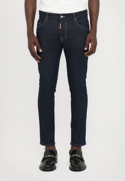 Dark blue denim jeans with a slim fit, featuring a standard five-pocket design and subtle stitching details. Worn with black loafers.