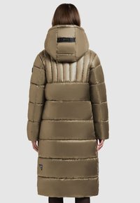 Cămașă verde măslinie cu umplutură, cu guler înalt, glugă mare și cusături orizontale. Prezintă o etichetă cu logo și un finisaj neted și lucios.