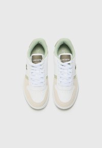 Lacoste-sneakers med hvit lær og beige semsket skinn, med lysegrønne detaljer. Rund tå, polstret krage og hvite lisser.