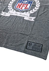 Gray T-shirt featuring a large NFL logo with red, white, and blue design; includes “From The Archives” text and a black label detailing recovery.