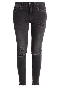 Jeans ajustados negros de mezclilla, con desgastes que presentan bordes deshilachados y detalles desgarrados en las rodillas. Diseño clásico de cinco bolsillos.