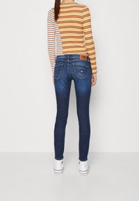 Smala jeans i mörkblå denim, med medelhög midja, bakfickor och en brun läderlapp med varumärkeslogotyp. Randig långärmad topp.