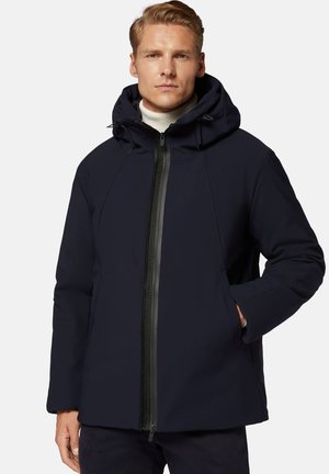 Giacca impermeabile blu navy con cappuccio rimovibile, chiusura frontale con zip, tasche laterali e finitura testurizzata. Presenta un design moderno e slanciato.