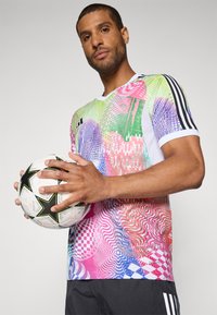 Colorful patterned soccer jersey in green, pink, and blue with white accents, paired with a black and white soccer ball featuring star designs.