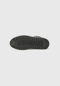 Semelle de chaussure en caoutchouc noire avec texture striée et logo "BOGNER" en relief, sur un fond blanc uni.