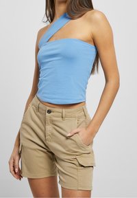 Ljusblå, åtsittande top med en axel gjord av bomull. I kombination med khaki cargo-shorts som når mitt på låret och har framfickor samt knäppning med knapp.