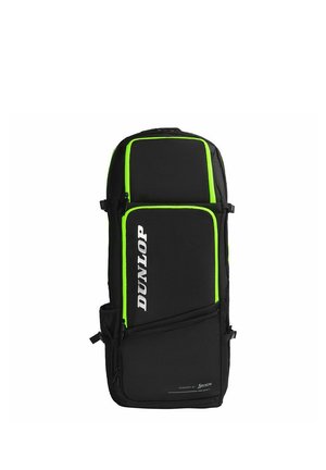 Mochila deportiva negra Dunlop con ribetes en verde neón, múltiples compartimentos con cremalleras y un bolsillo lateral de malla, colocada de pie sobre un fondo blanco.