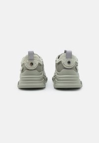 Sneaker grigie chiare con tessuto testurizzato e dettagli in rete. Presentano un collare imbottito, un tallone rinforzato e una linguetta sul retro.