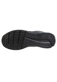 Svart atletisk skosula med texturerad gummi, som har djupa fåror och mönster för bra grepp, samt en slank design med en böjd kontur.