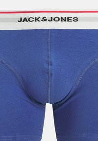 Boxer-Shorts bleus pour hommes en coton, avec une ceinture élastique blanche, grise et rouge portant l'inscription "JACK&JONES". Texture lisse, design ajusté.