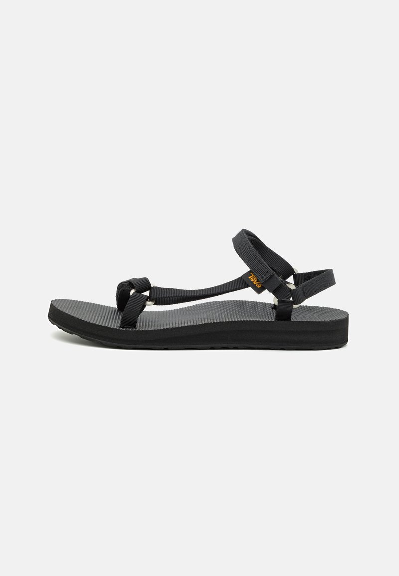 Black sandals with a textured sole, featuring adjustable fabric straps and a flat design. The footbed has a slight curve for comfort.