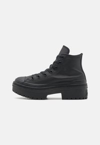 Černé vysoké tenisky s gumovou podrážkou, ozdobené šněrováním, kulatou špičkou a texturovaným koženým svrškem. Robustní design podrážky.