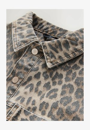 Jeanshemd mit Leopardenmuster, das einen strukturierten Kragen, braune Knopfakzente und kontrastierende Nähte auf einem beigen Hintergrund aufweist.