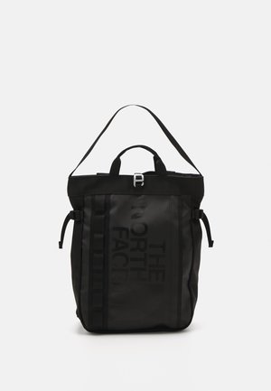 Zwarte roll-top rugzak gemaakt van duurzaam materiaal met verstelbare banden, klittenbandsluiting en reliëflogo op de voorkant.