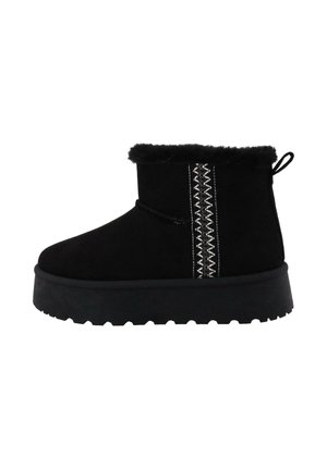 Black ankle boot with fur lining, thick sole, decorative white zigzag stitching on the side, and a pull tab at the back.