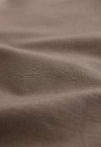 Tela marrón con un tejido texturizado, que muestra ondas suaves y sutiles variaciones en el tono y la superficie. Ideal para diversas aplicaciones textiles.